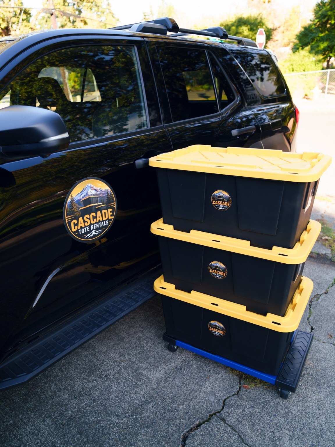 A stack of Cascade black and yellow moving totes on a dolly